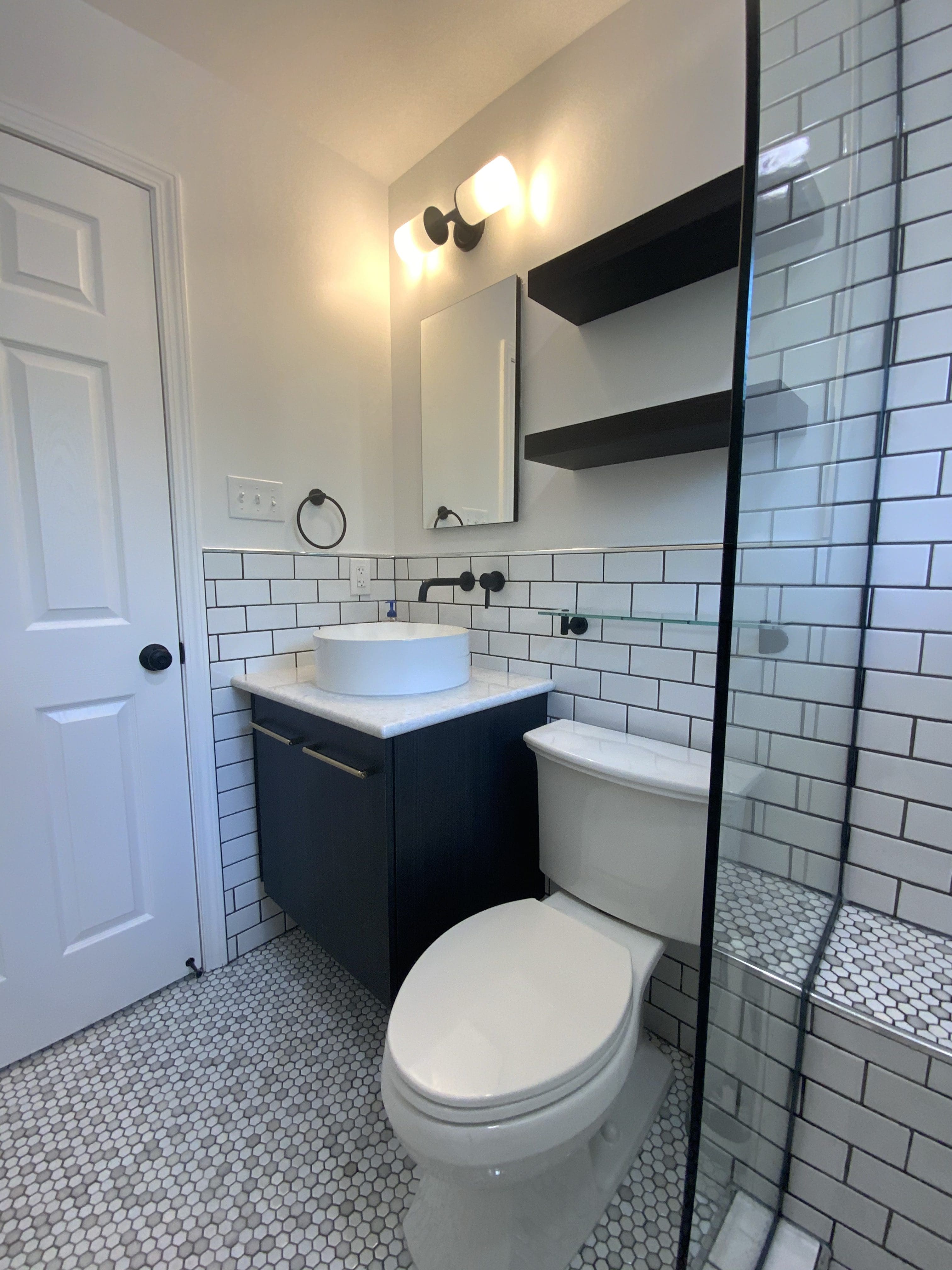 Small luxury bathroom in a black and white color scheme used to demonstrate how expensive bathroom remodeling is.