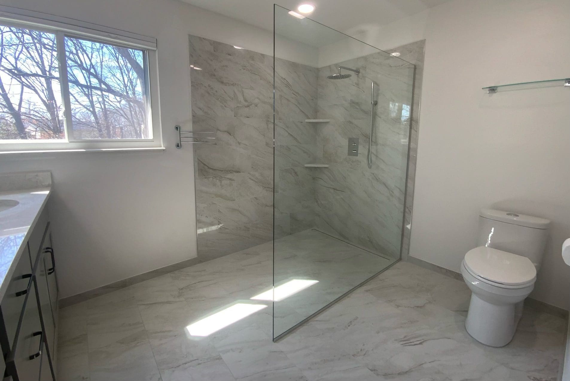 A curbless shower, with white tile and chrome hardware.