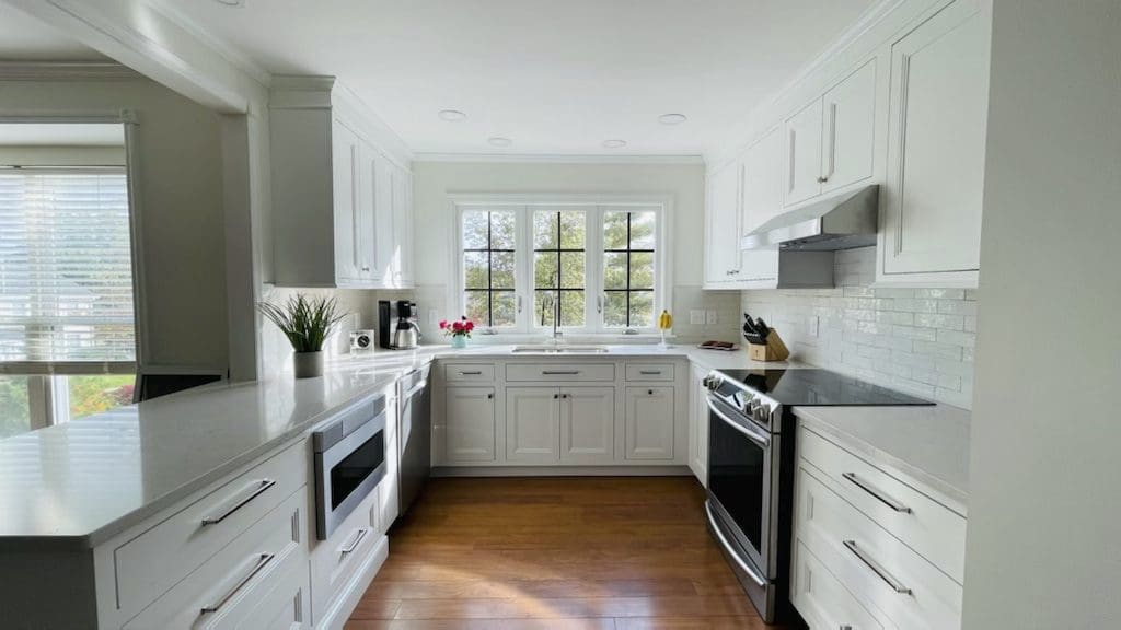 A designer kitchen on the smaller side, featuring a black and white color palette and stainless steel appliances.
