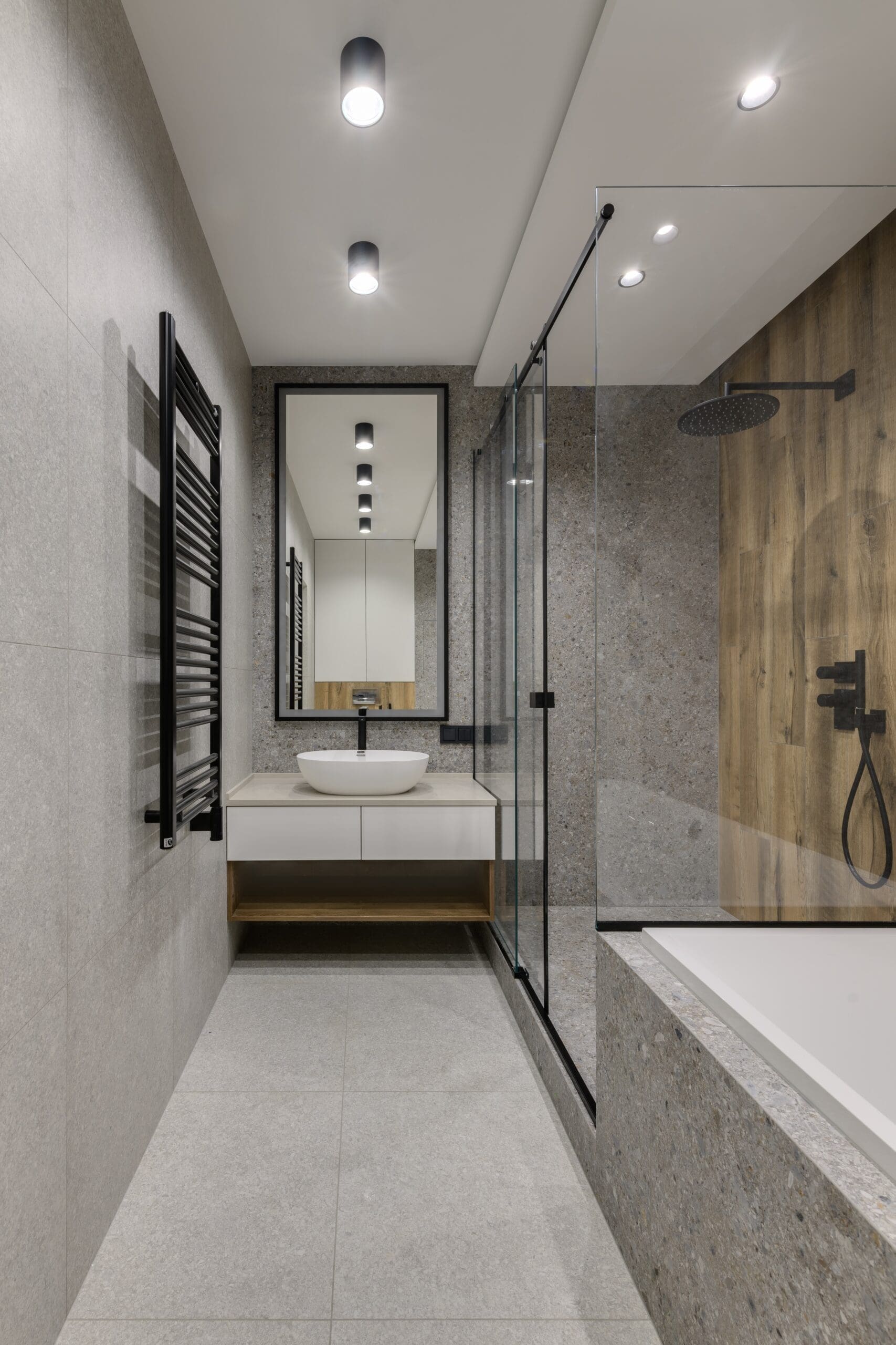 A small bathroom featuring a shower curb with grey and wood-tone tile.