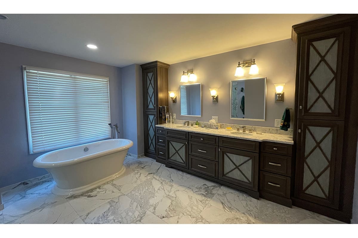 A large master bathroom remodel in Manchester, MO featuring marble floor tile and a freestanding tub alongside a large vanity.